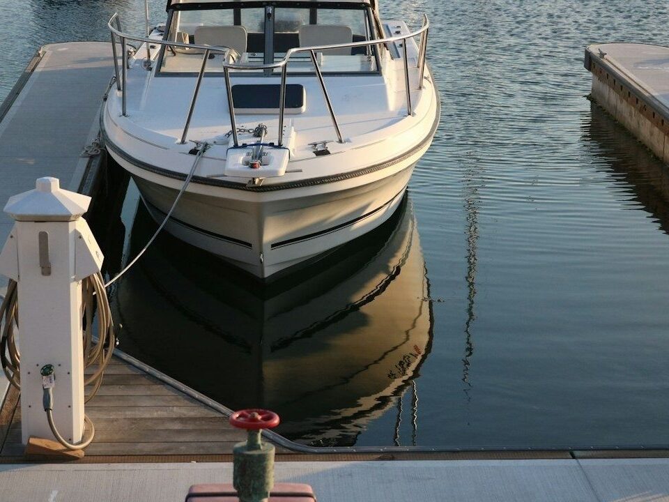 Båt vid brygga med ansluten slang och elstolpe